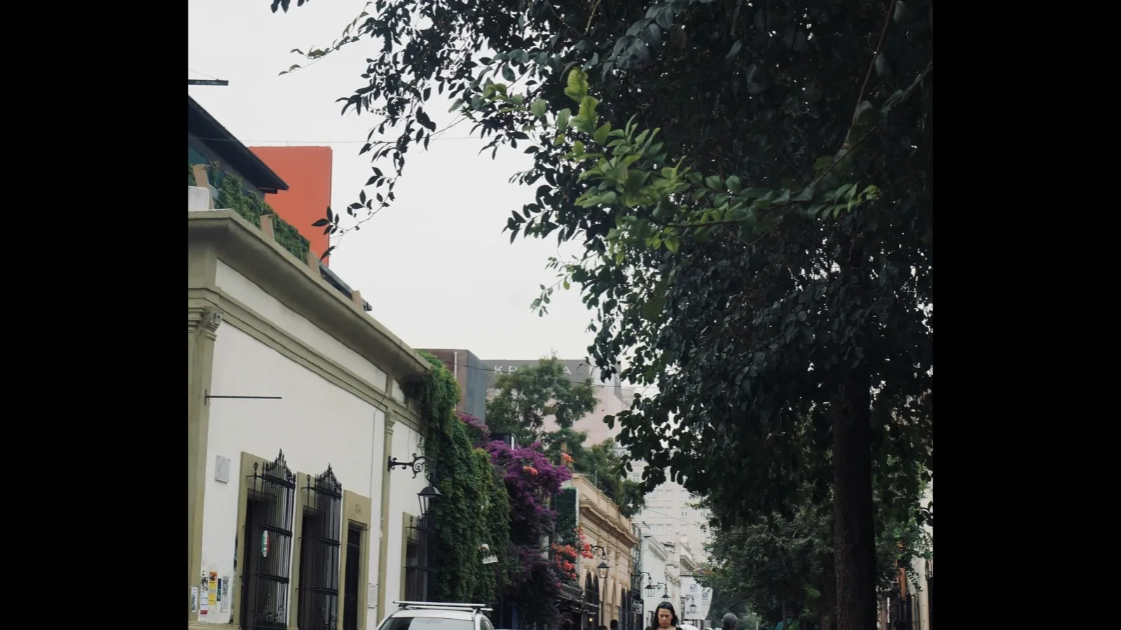A car and pedestrians on a historic street in Monterrey's Barrio Antiguo