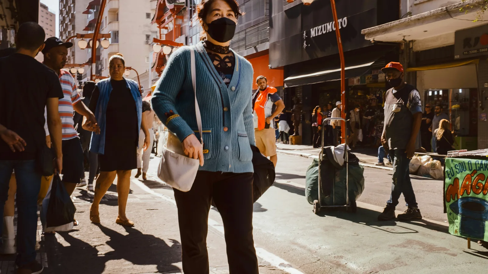 A masked pedestrian on a city street in Sao Paulo